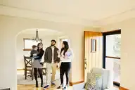 Family smiles and looks around living room of their home