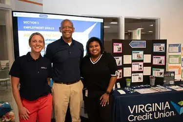 Member's of VACU Financial Education team posing in front of "Unlocking Success" booth