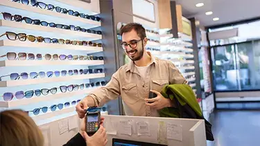 Man smiles while using credit card to make a purchase at an eyewear store