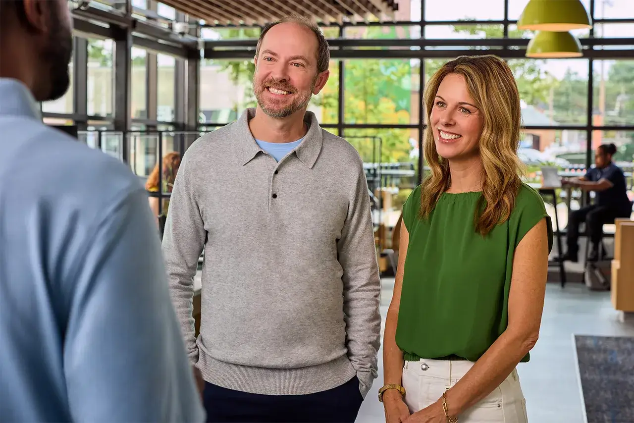 Man and woman smile while speaking with a Virginia Credit Union employee