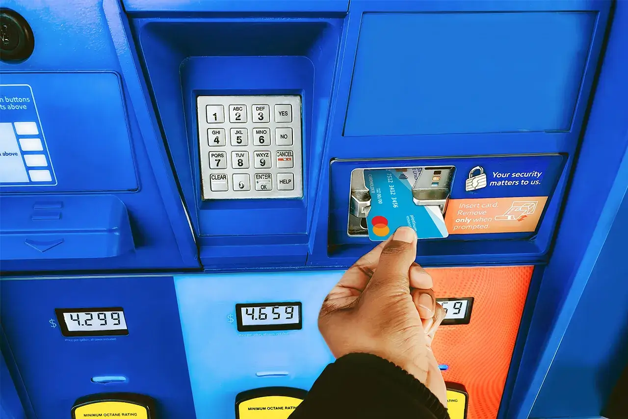 Individual using credit card to pay at gas station pump