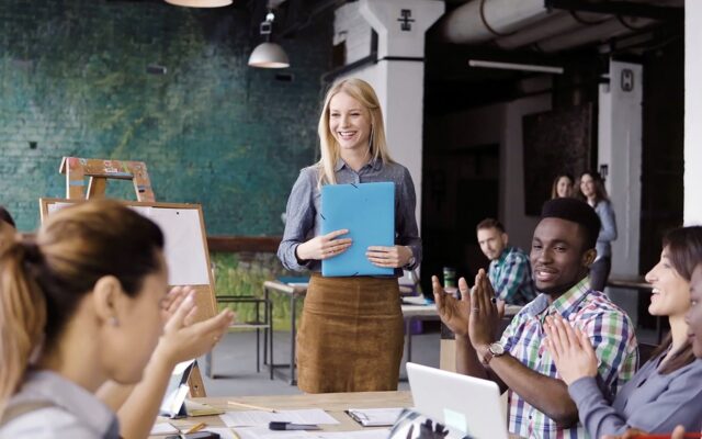 Professional woman gives presentation to applauding team members 978b8d064138018a1dfad71b9882dd21