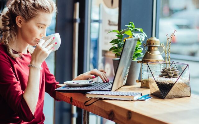 Young woman sips coffee and views laptop in cafe 978b8d064138018a1dfad71b9882dd21