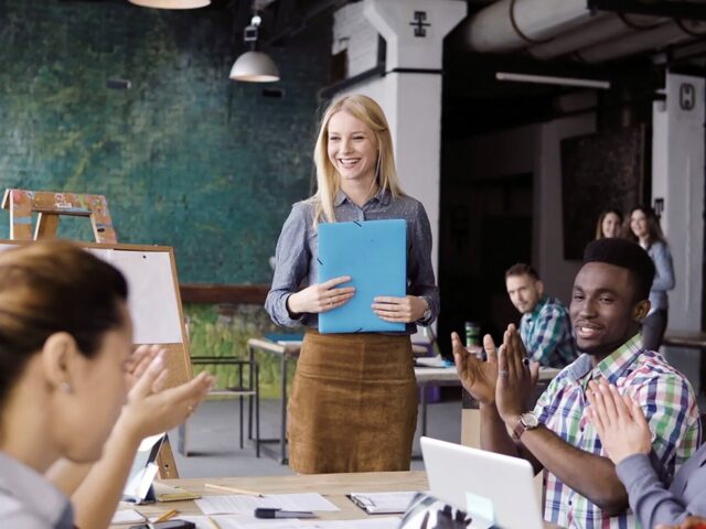 Professional woman gives presentation to applauding team members 978b8d064138018a1dfad71b9882dd21