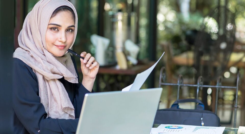 Young woman sits at cafe table with laptop and budget charts 978b8d064138018a1dfad71b9882dd21